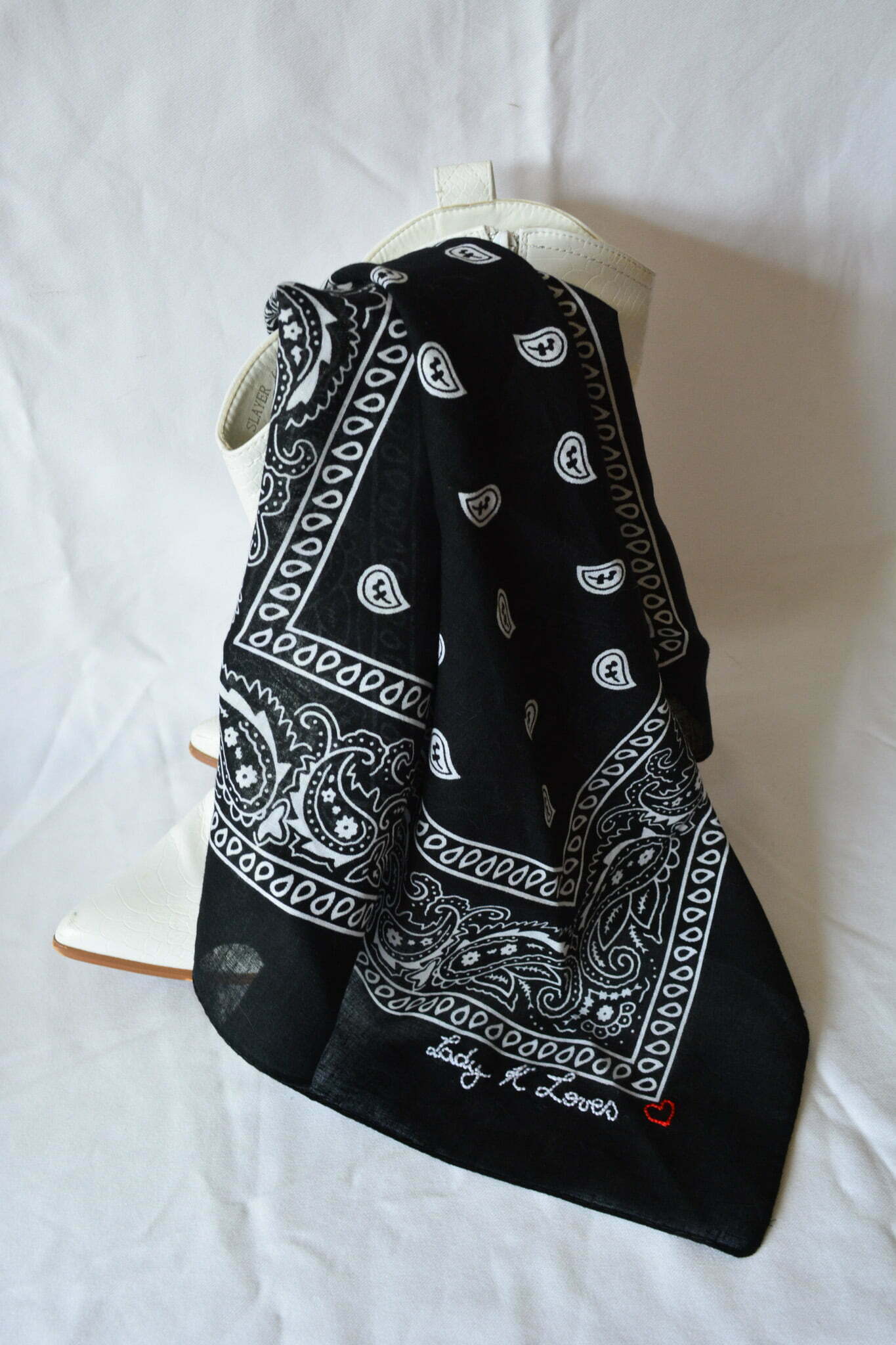 black paisley scarf draped over white cowboy boots